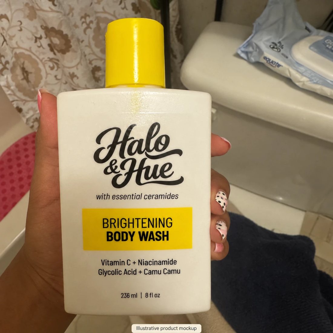 Hand holding the Brightening Body Wash in a bathroom