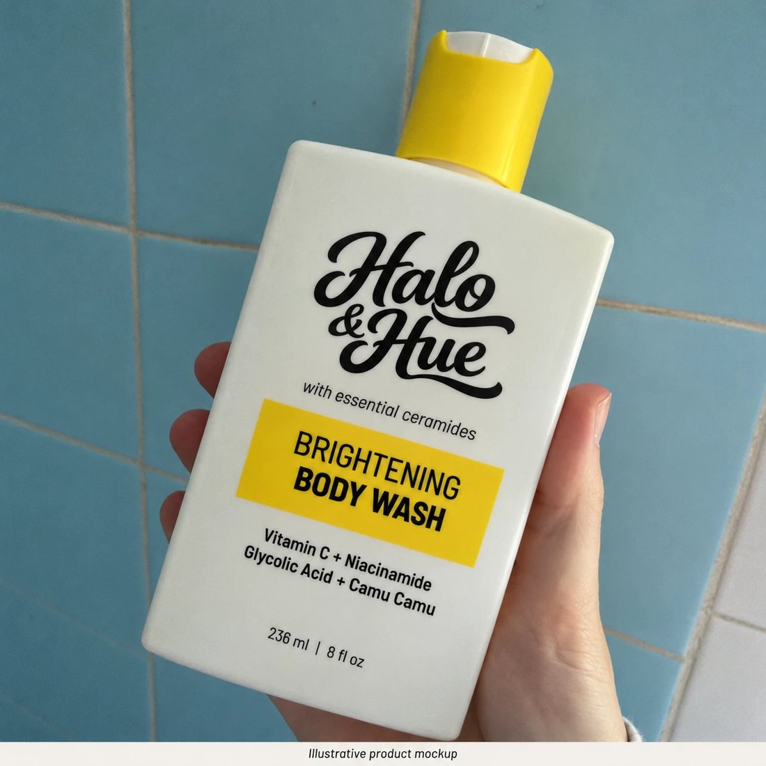Hand holding the Brightening Body Wash against shower tiles